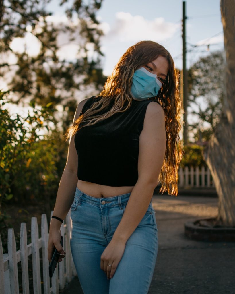 a woman wearing a face mask and jeans